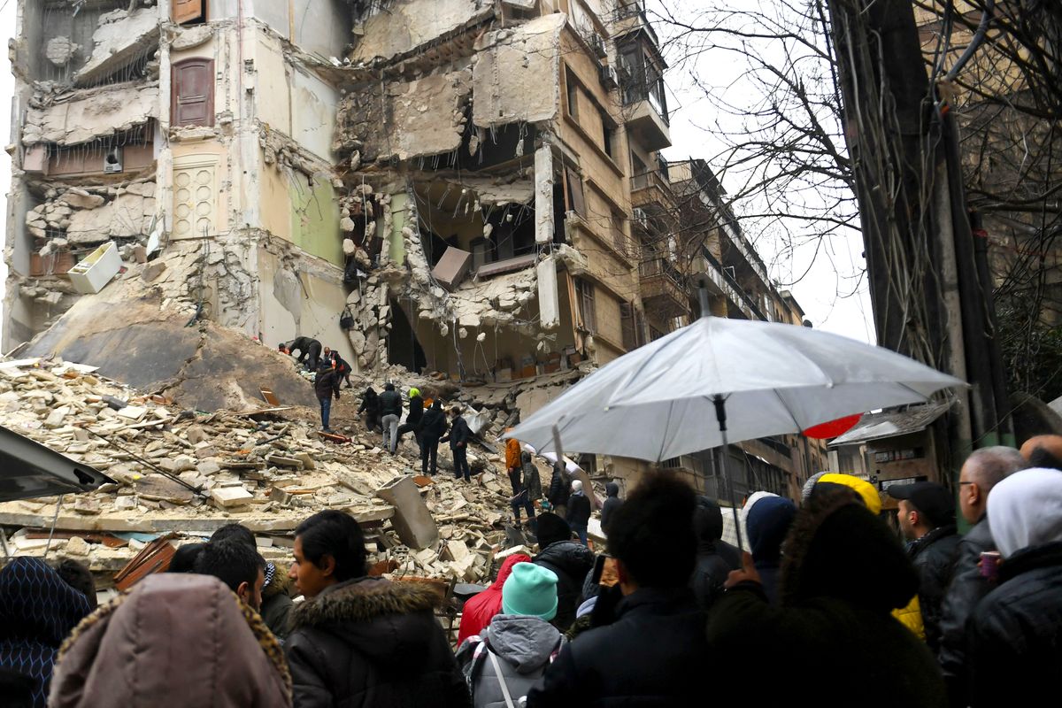 onlookers watch as rescue teams look for survivors under the rubble of a collapsed building after an earthquake in the regime controlled northern syrian city of aleppo on february 6 2023