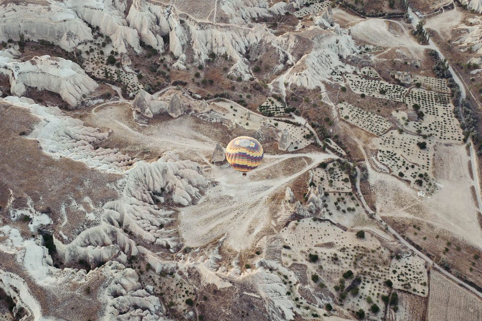 In deze vogelvluchtopname is n enkele heteluchtballon boven het gemarmerde landschap van Cappadoci te zien