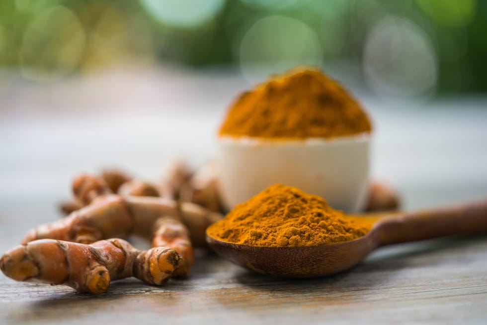 turmeric powder and fresh turmeric in wood bowls on wooden table