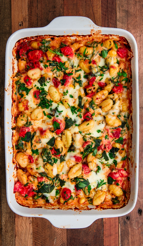 tuscan butter gnocchi with spinach and tomatoes in a white baking dish