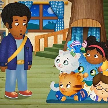 daniel tiger plays in a pile with his friends while an adult looks look with a surprised look on his face in a scene from daniel tiger's neighborhood, a good housekeeping pick for best toddler tv shows