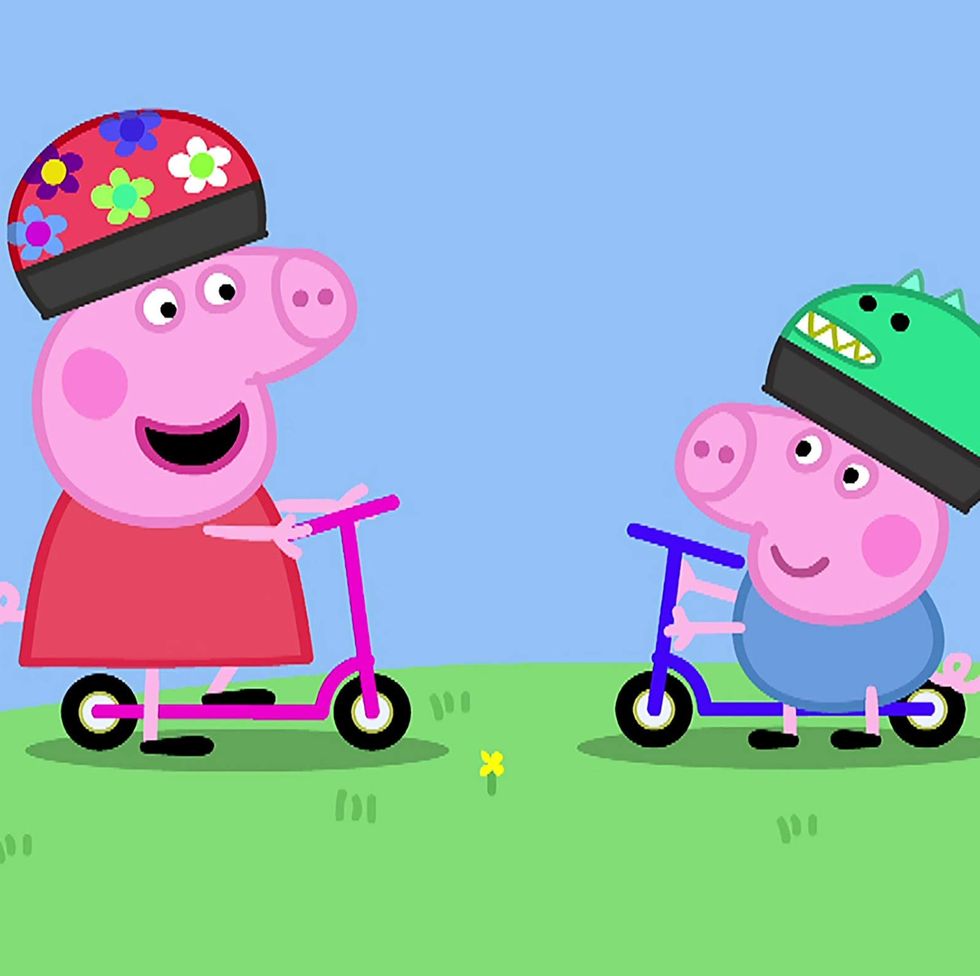 peppa and george wear helmets and ride scooters in a scene from peppa pig, a good housekeeping pick for best toddler tv shows