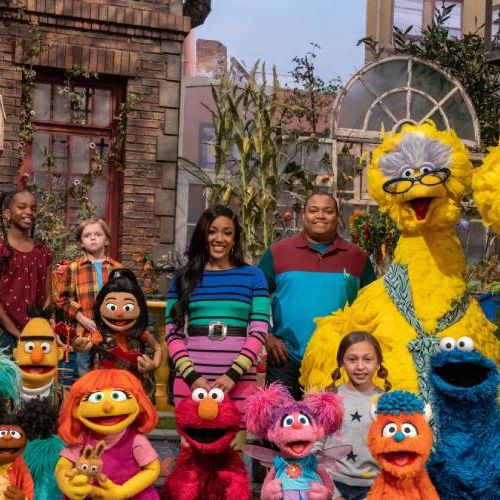 the cast of humans and puppets pose happily in a promotional image for sesame street, a good housekeeping pick for best toddler tv shows
