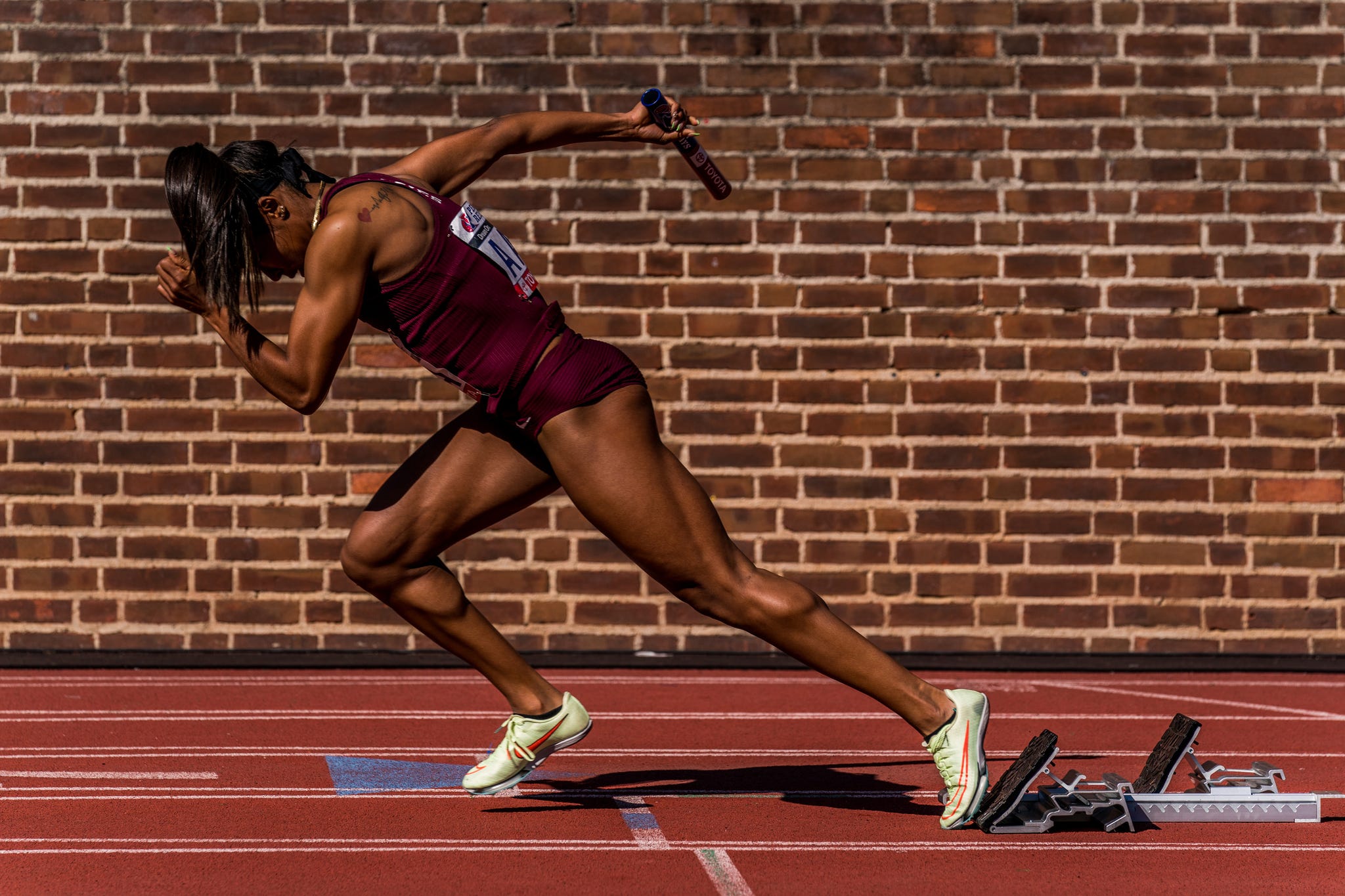 RWD a woman sprints out of blocks in front of a brick background