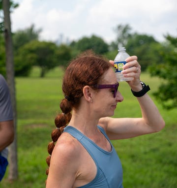 runner holding cold water to her head after workout runner holding cold water to her head after workout