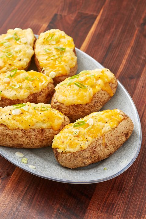 cheesy twice baked potatoes on a blue plate on a dark wood background