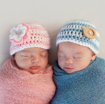 five week old sleeping boy and girl fraternal twin newborn babies they are wearing crocheted pink and blue striped hats