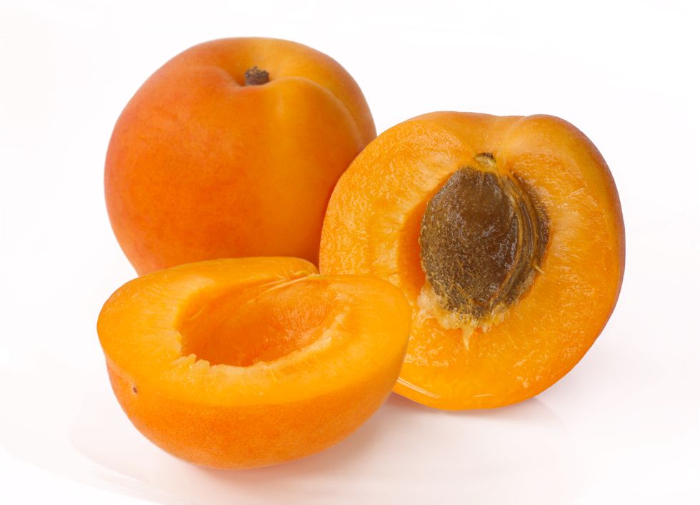 two apricots with one cut in half to reveal stone