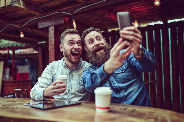 Two Bearded Friends Drinking Coffee and Taking Selfie in Restaurant
