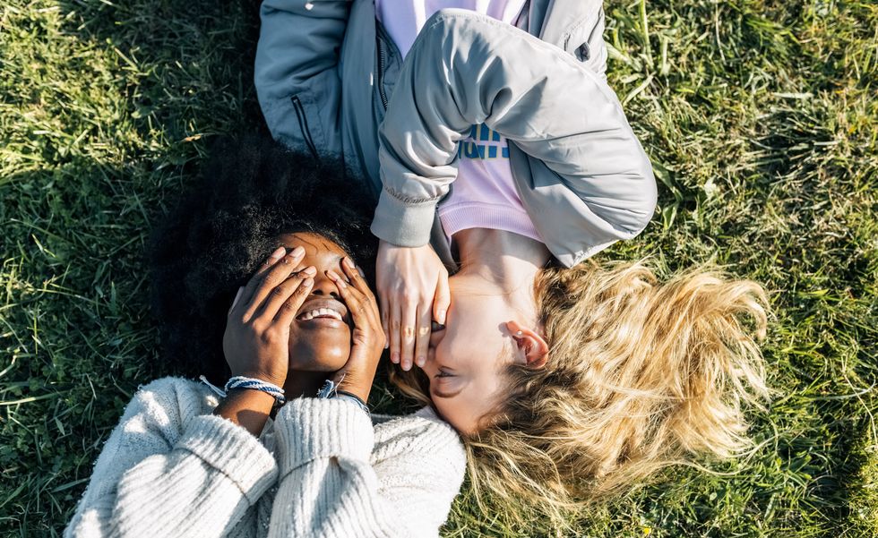 two best friends telling secrets lying in the grass