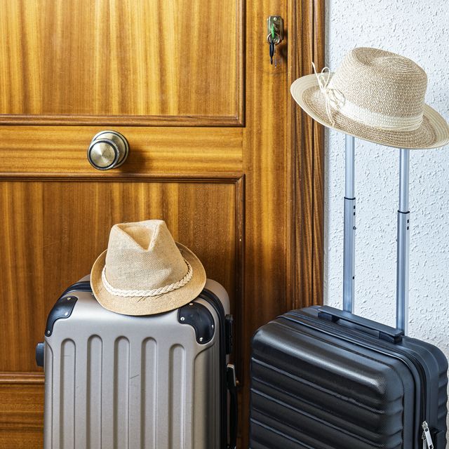 two carry on suitcases and two hats next to the entrance door of a tourist rental apartment.