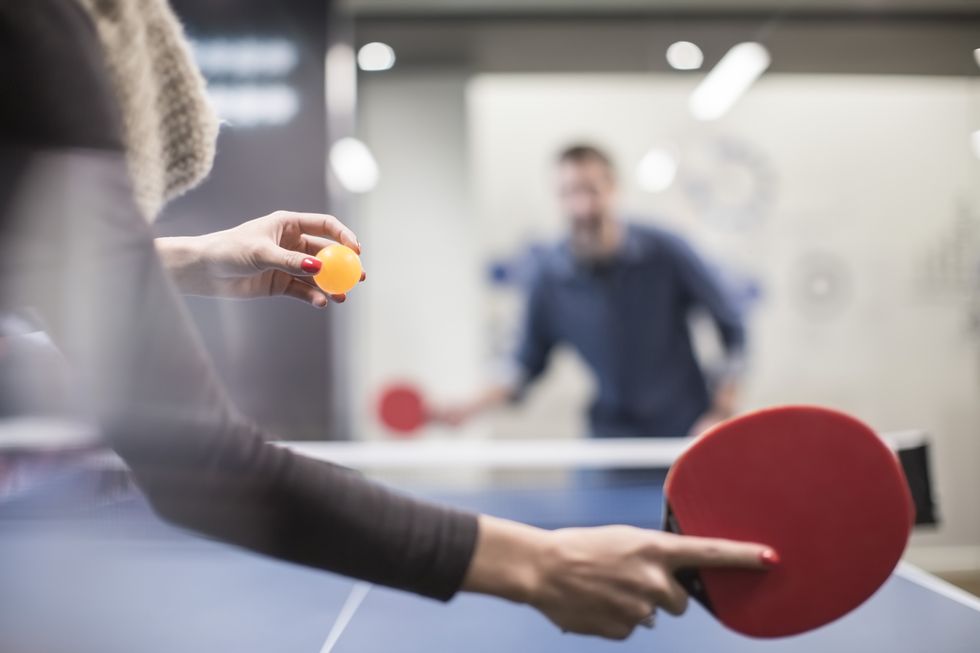 two colleagues playing table tennis in office break room