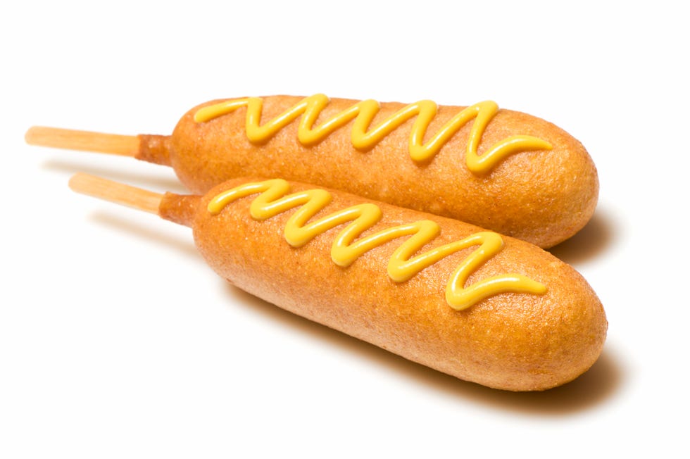 Two corn dogs with mustard isolated on white background