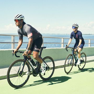 two cyclists riding on a bridge in miami in the sunshine