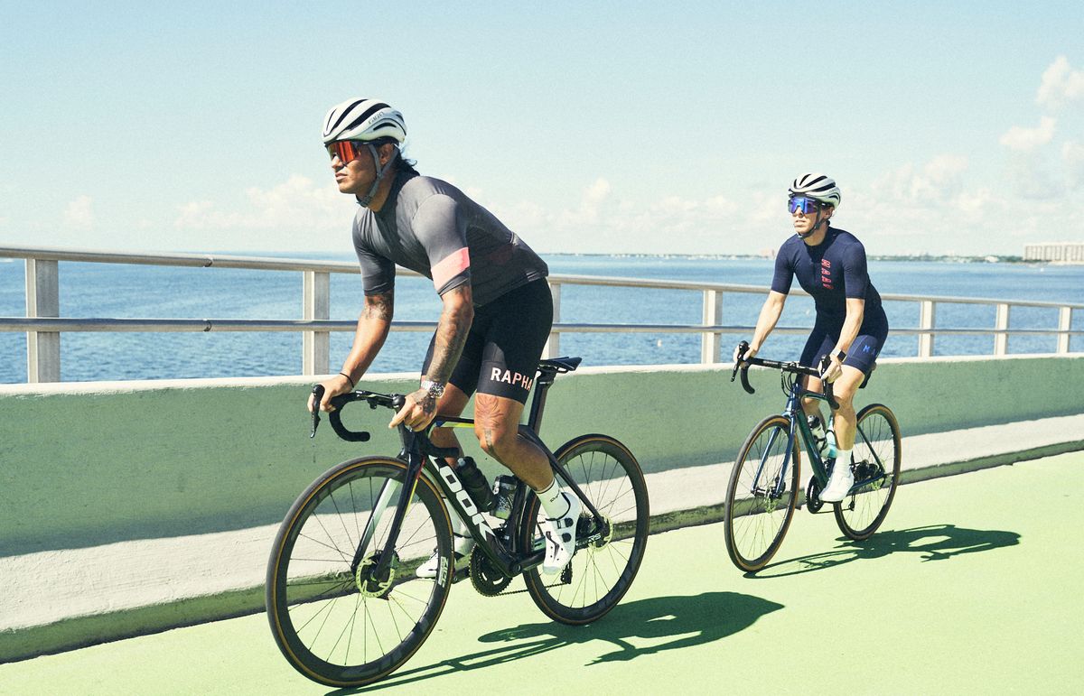 two cyclists riding on a bridge in miami in the sunshine