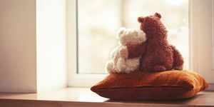 Two embracing teddy bear toys sitting on window-sill