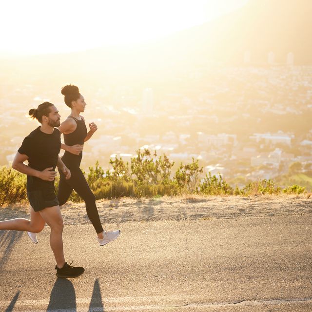 two fit young people jogging together along a scenic road