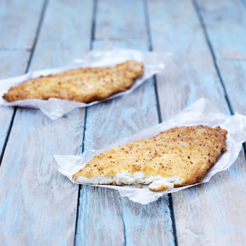 two fried breaded flounder fish pieces on wooden table