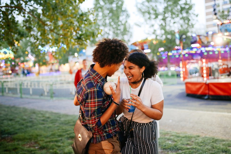 Two friends at funfair, laughing, boy holding ball