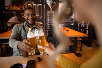 two friends drinking beer and talking in a bar