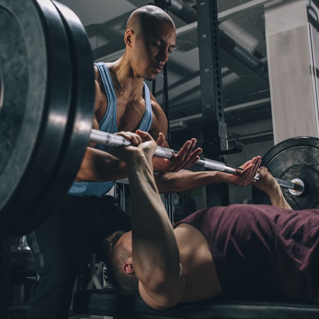 Two friends exercising bench press in gym
