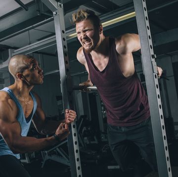 two friends exercising dips at power rack in gym