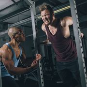 two friends exercising dips at power rack in gym