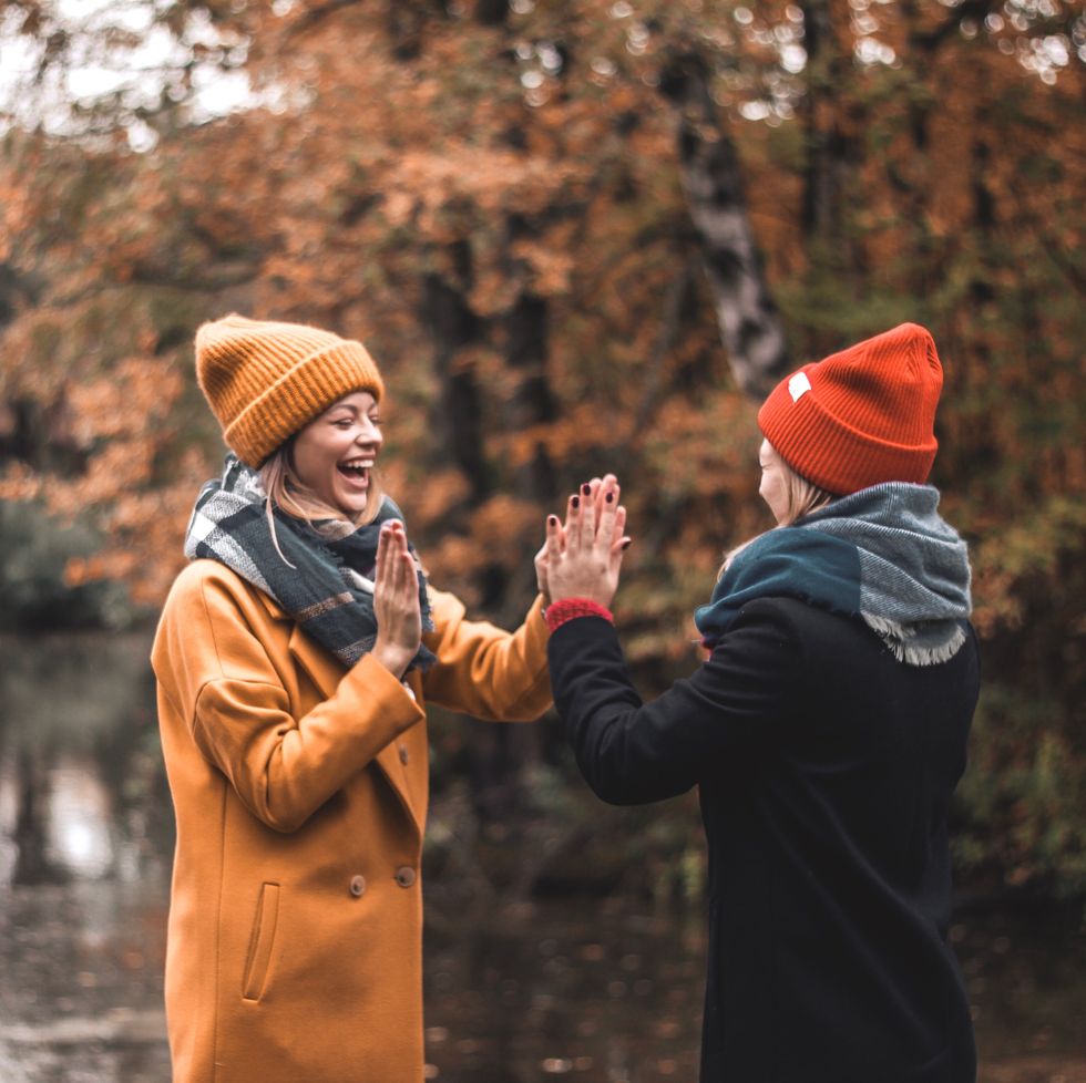 two friends high fiving at fall lake