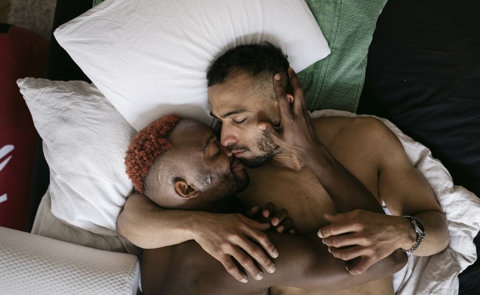 two gay men fondly embracing in bed