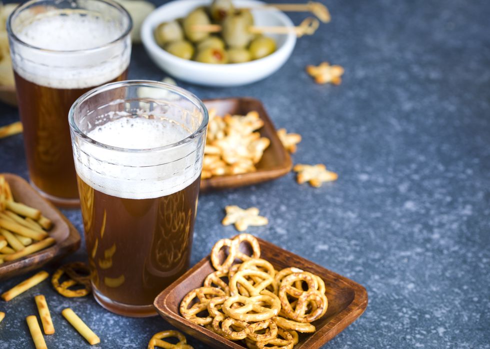 Two glasses of beer and snacks on stone background with copy space