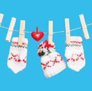 Two gloves, hat and heart on clothesline with clothespins, blue background
