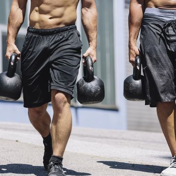 two gym athletes doing farmer's walk with kettlebells