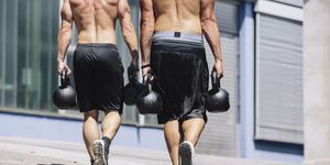 two gym athletes doing farmer's walk with kettlebells
