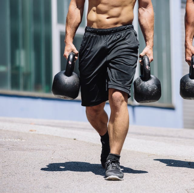 two gym athletes doing farmers walk with kettlebells