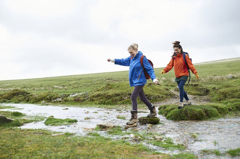 two hikers crossing stream in countryside
