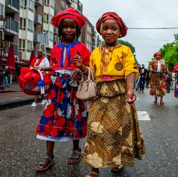 twee jonge meisjes in traditionele surinaamse kledij in optocht bigi spikri op ketikoti