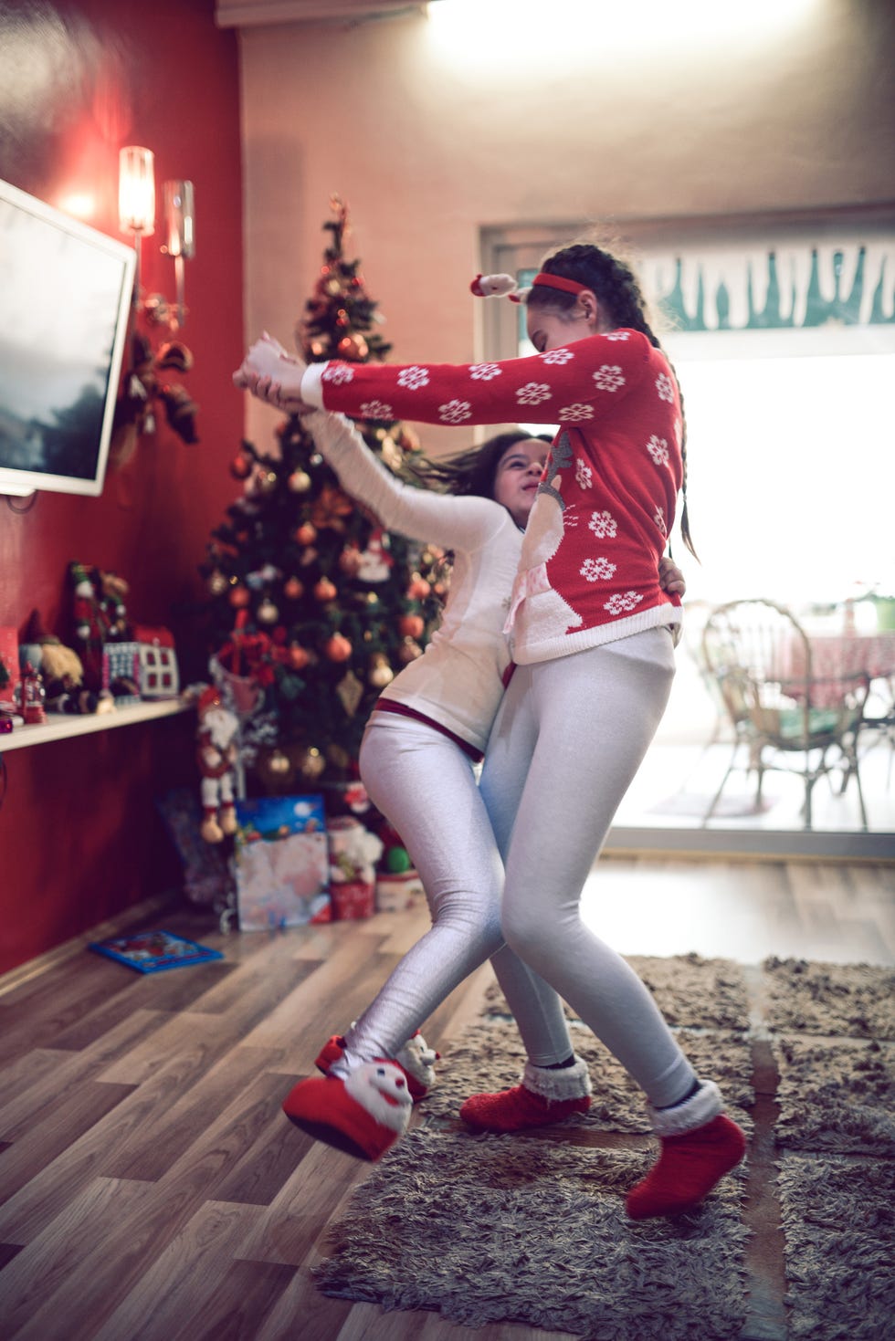 two little girls dancing by christmas tree