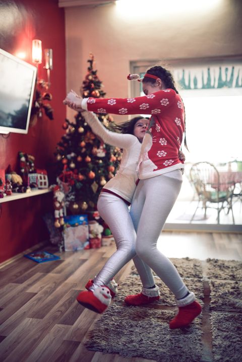 two little girls dancing by christmas tree on new year morning