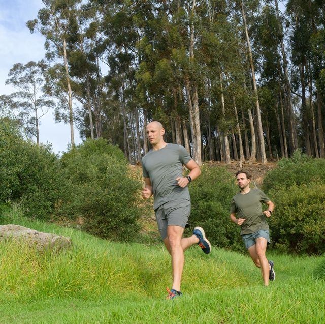 two male runners running together on grass field low angle view full length