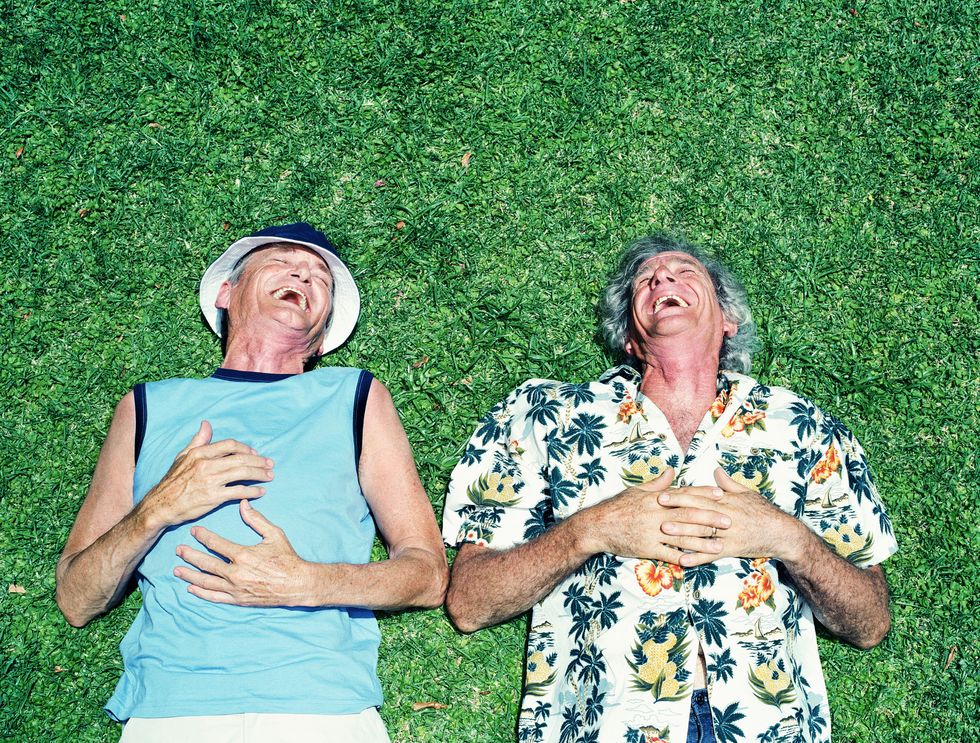 two mature men lying on grass, laughing, overhead view