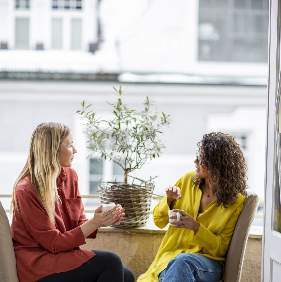 two mature woman talking together on small and cozy balcony