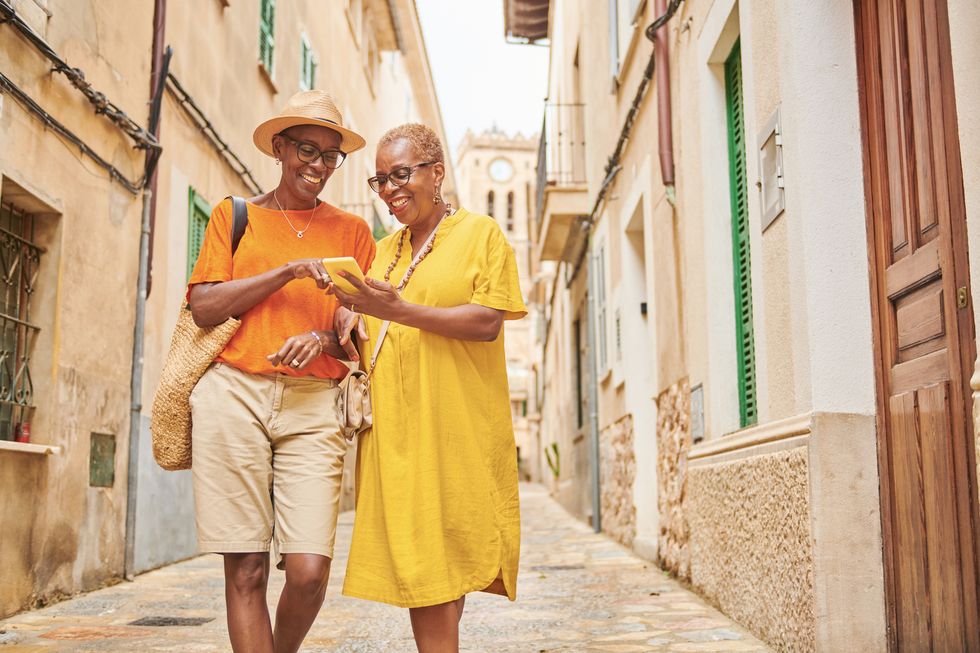 two mature women walking together exploring an old town in europe