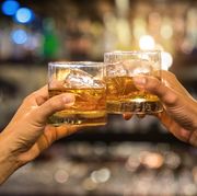 two men clinking glasses of whiskey drink alcohol beverage together at counter in the pub