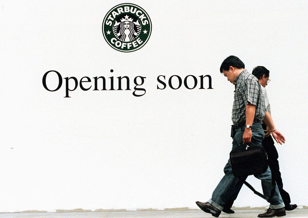 Two men cross paths in front of an advertisement a