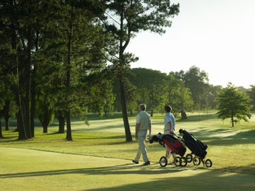 two men pulling golf push carts on a course