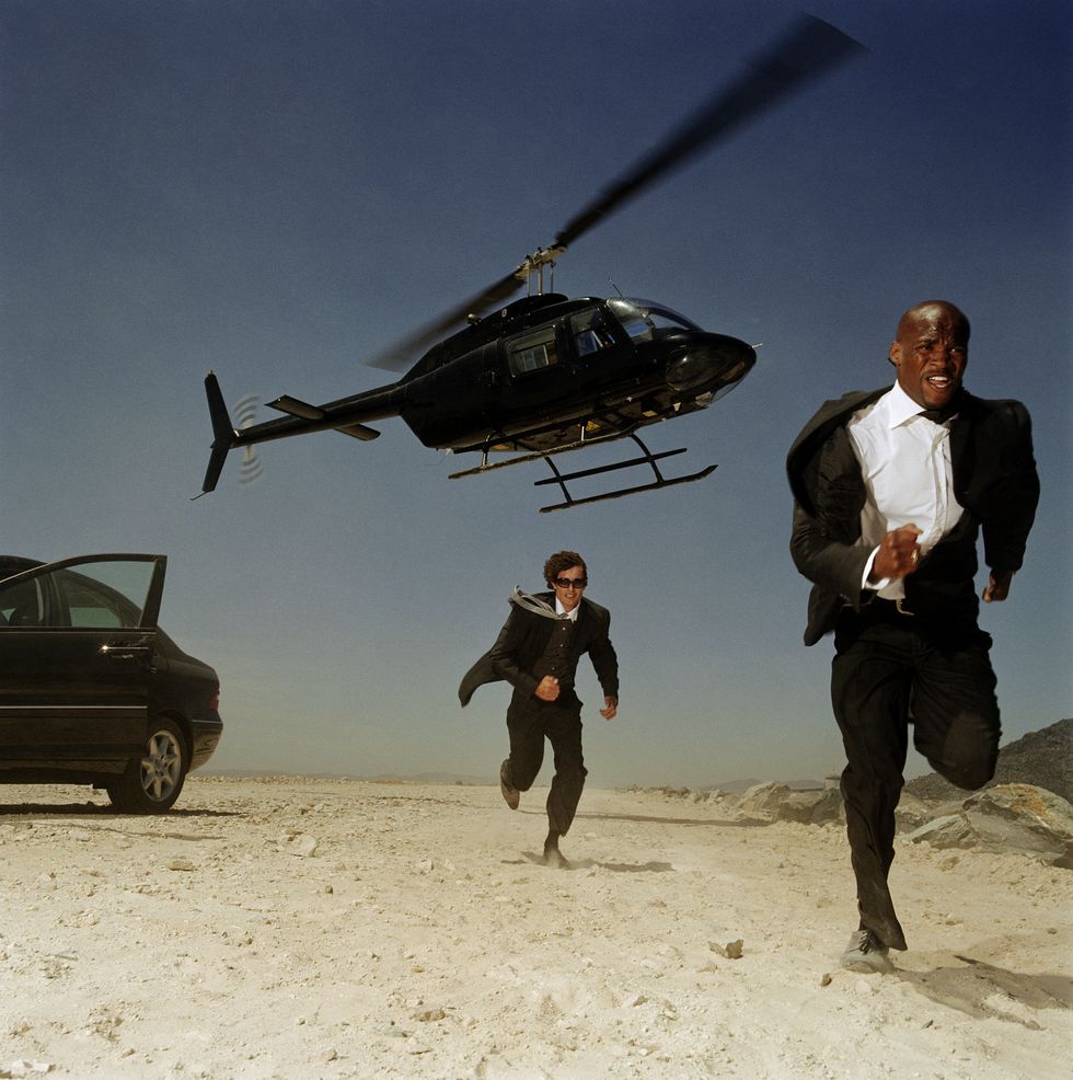 two men running from helicopter in desert
