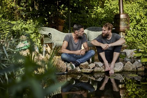 two men sitting together at garden pond talking