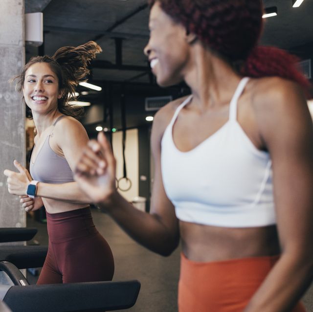 two motivated sportswomen exercising on a treadmill at the gym