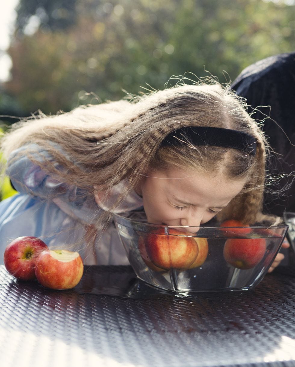 two older children playing halloween bobbing for apples game