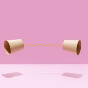 two paper cups united with a yellow string on a pink background